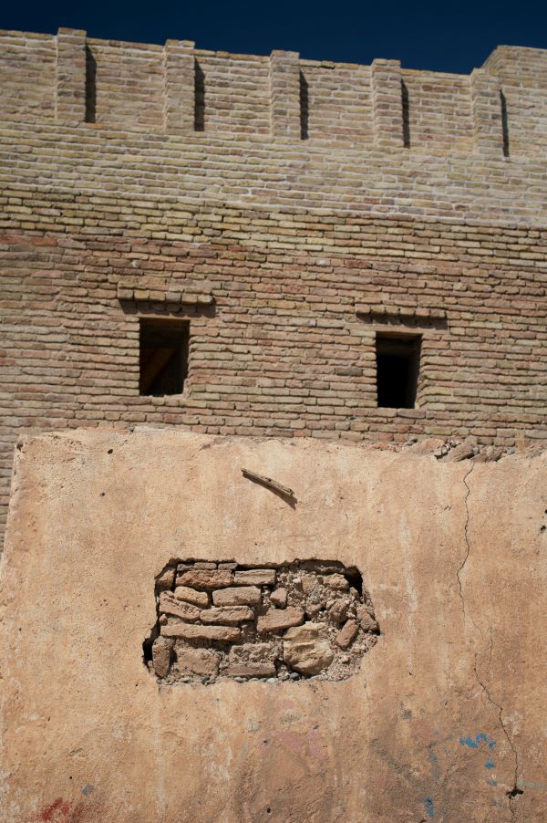 Picture of an old brick wall with two window openings at the top and a cracked section below, resembling eyes and a mouth, illustrating the pareidolia phenomenon.